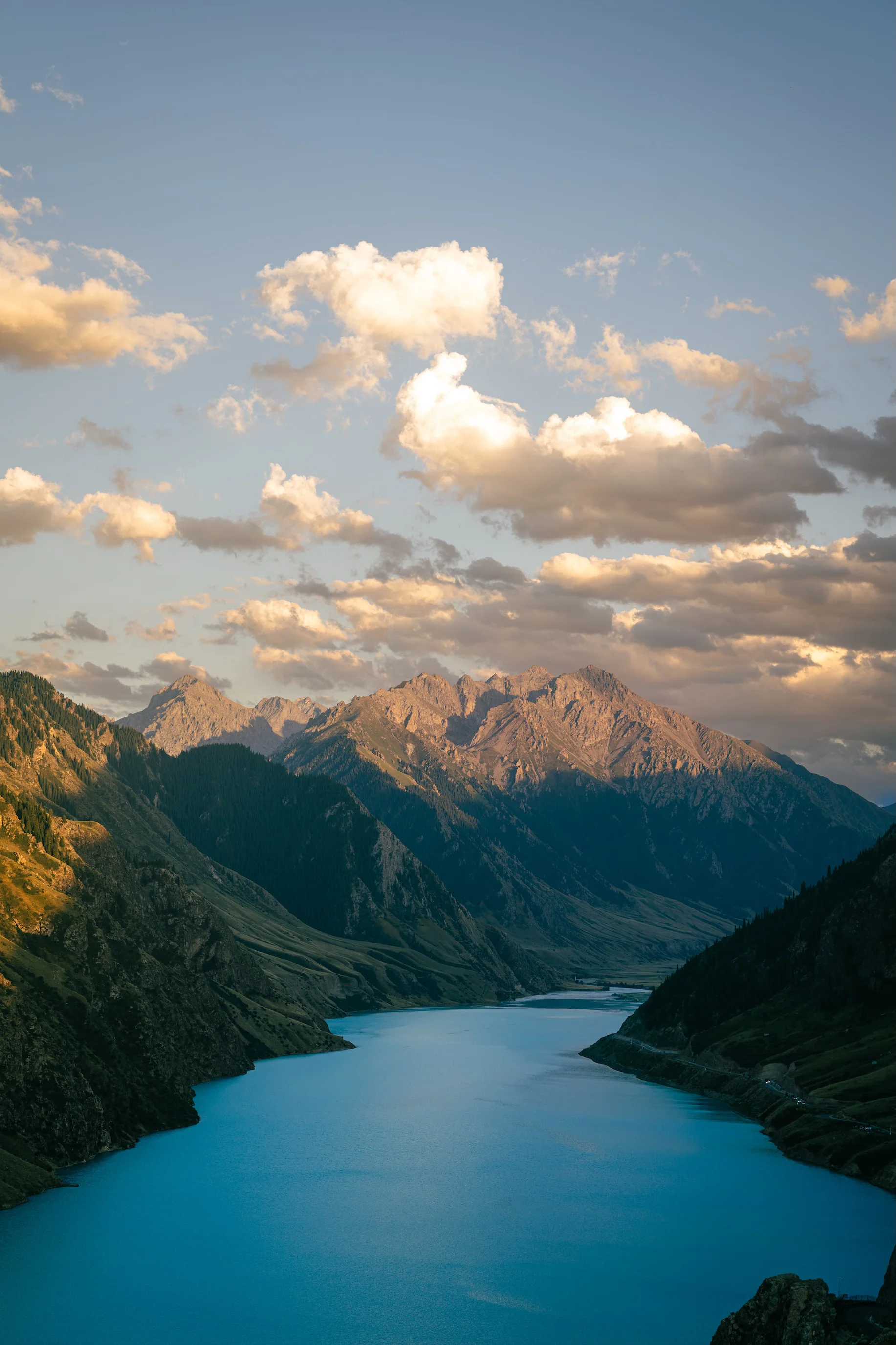 A turquoise reservoir in a canyon under alpenglow peaks